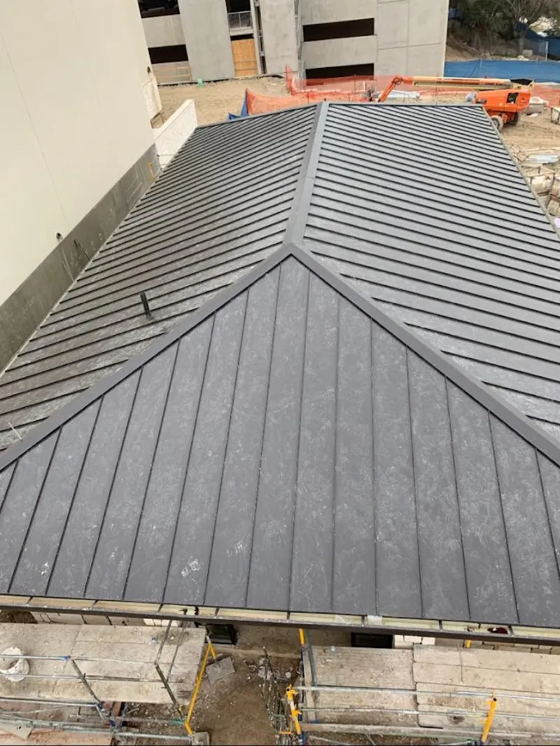 Commercial metal roof construction with crane equipment in Perry